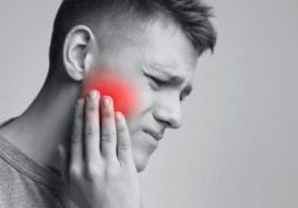 Dental problem. Young man suffering from strong toothache, monochrome photo with red inflamed zone, free space